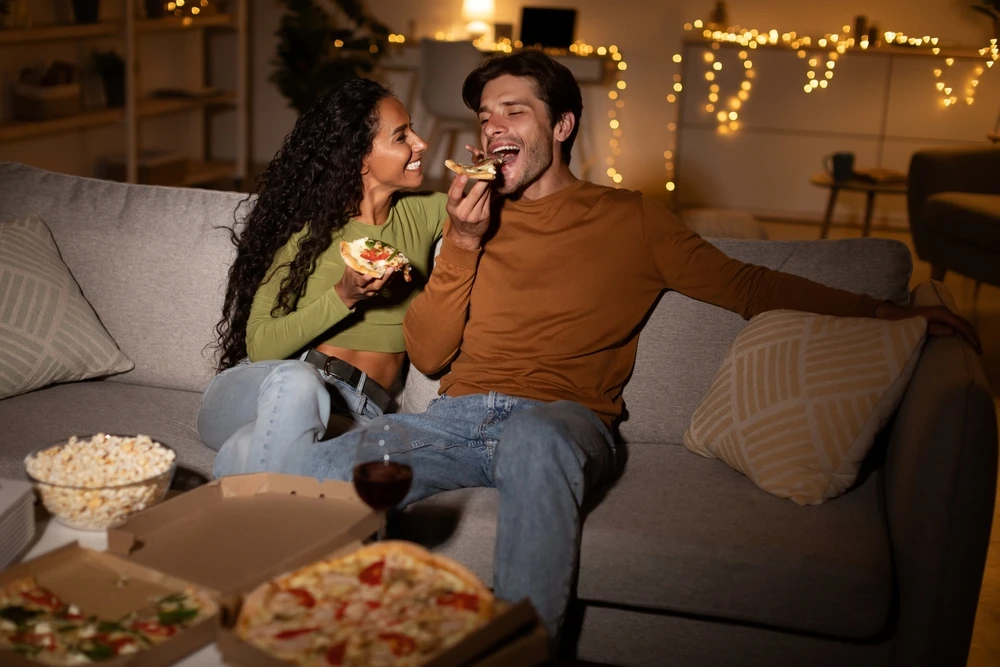 Man and women enjoying pizza on the couch